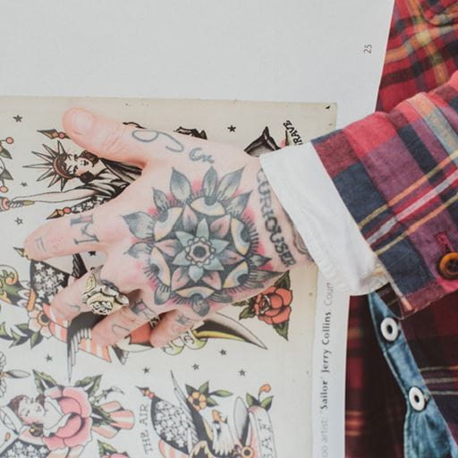 Close shot of tatooed hand holding tattoo book