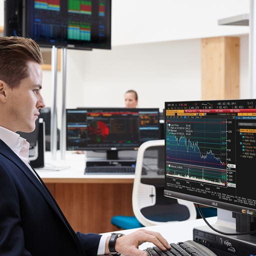 Male student sitting at computer showing financial trading on the screen 