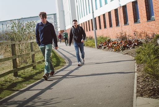 Two students walking along a footpath past the Meadows accommodation