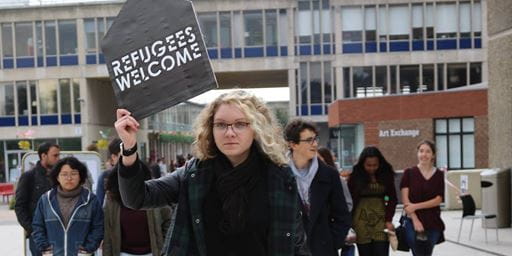 students marching through the squares at the University of Essex holding a "refugees welcome" sign