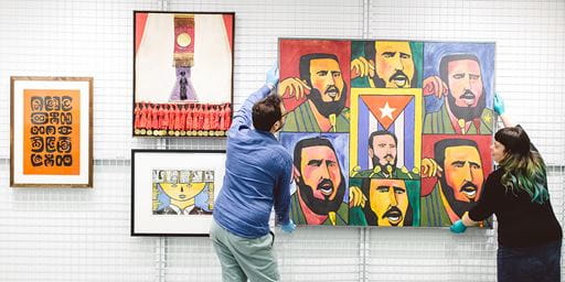 two members of staff hanging art in a gallery