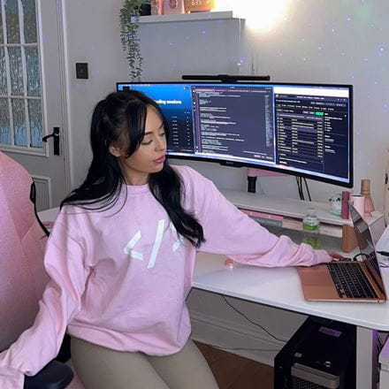 Dr Liv Grant sitting at her home desk with three monitors and a rose gold laptop.