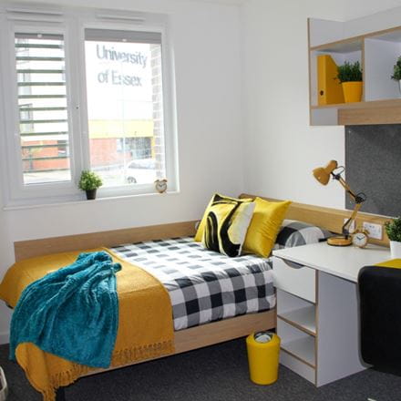 bed in front of a window with a desk to the right