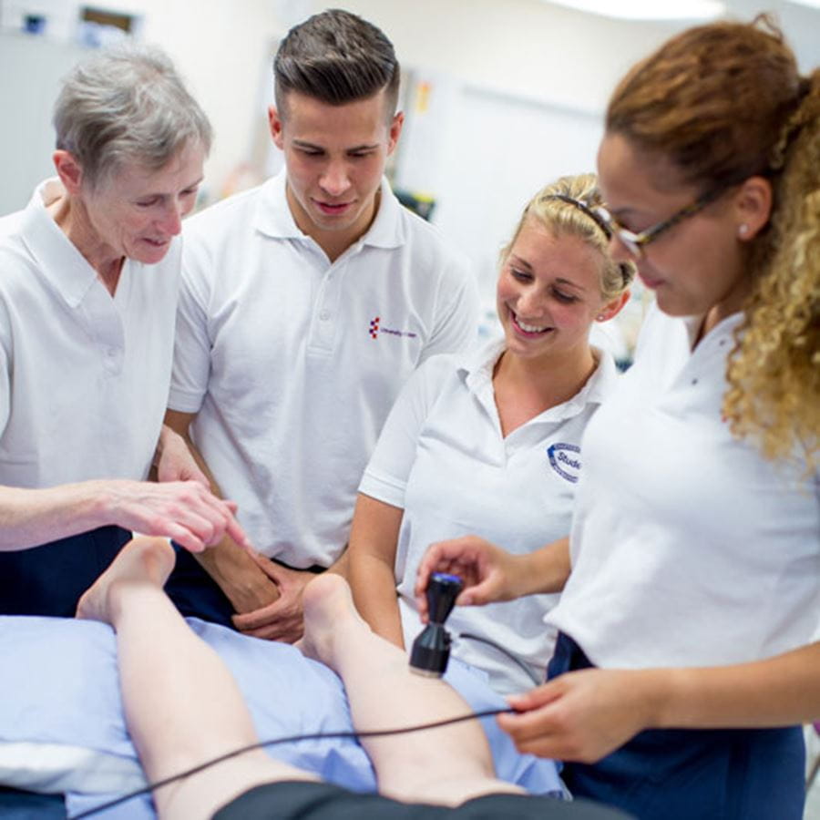 3 students with teacher looking at a body