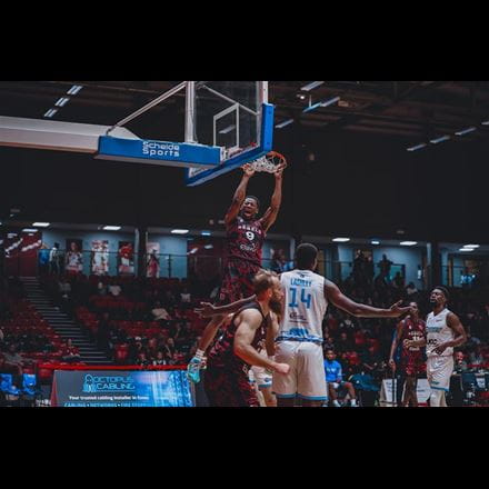 Rebels player jumping up to basket ball hoop during a match