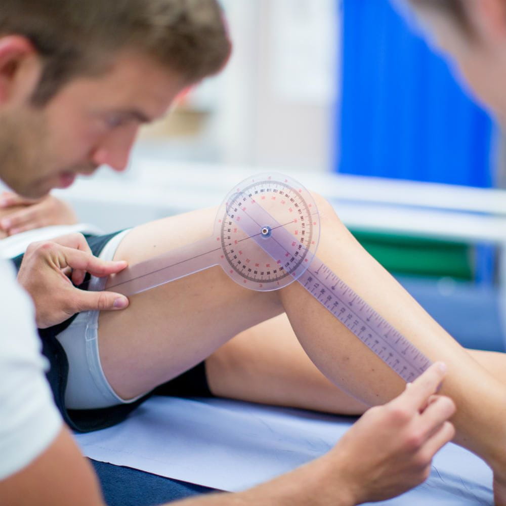 A student using a protractor to check the angle of a persons knee.