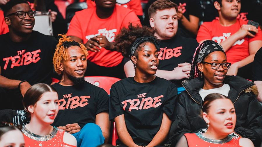 Students watching a Rebels game wearing black and red Tribe tshirts
