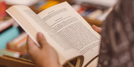 A close-up of a student reading a book at a book sale.